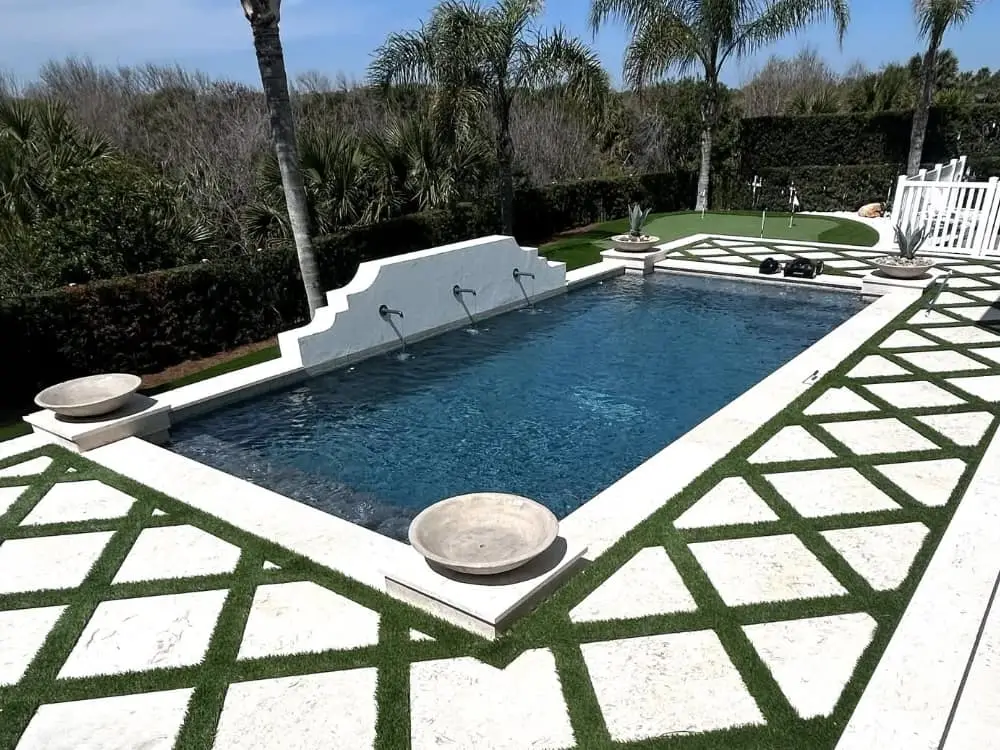 geometric pool, artificial turf between travertine paver deck